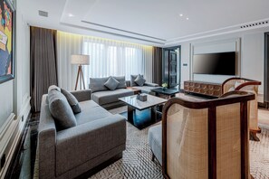 A modern hotel room with a grey sofa, a small coffee table, a TV, and a unique wooden chair. - UrCove by Hyatt Beijing Guomao Sanlitun (Beijing)