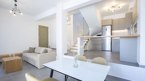 Un espacio habitable moderno con comedor, sofá, mesa de centro y cocina al fondo.