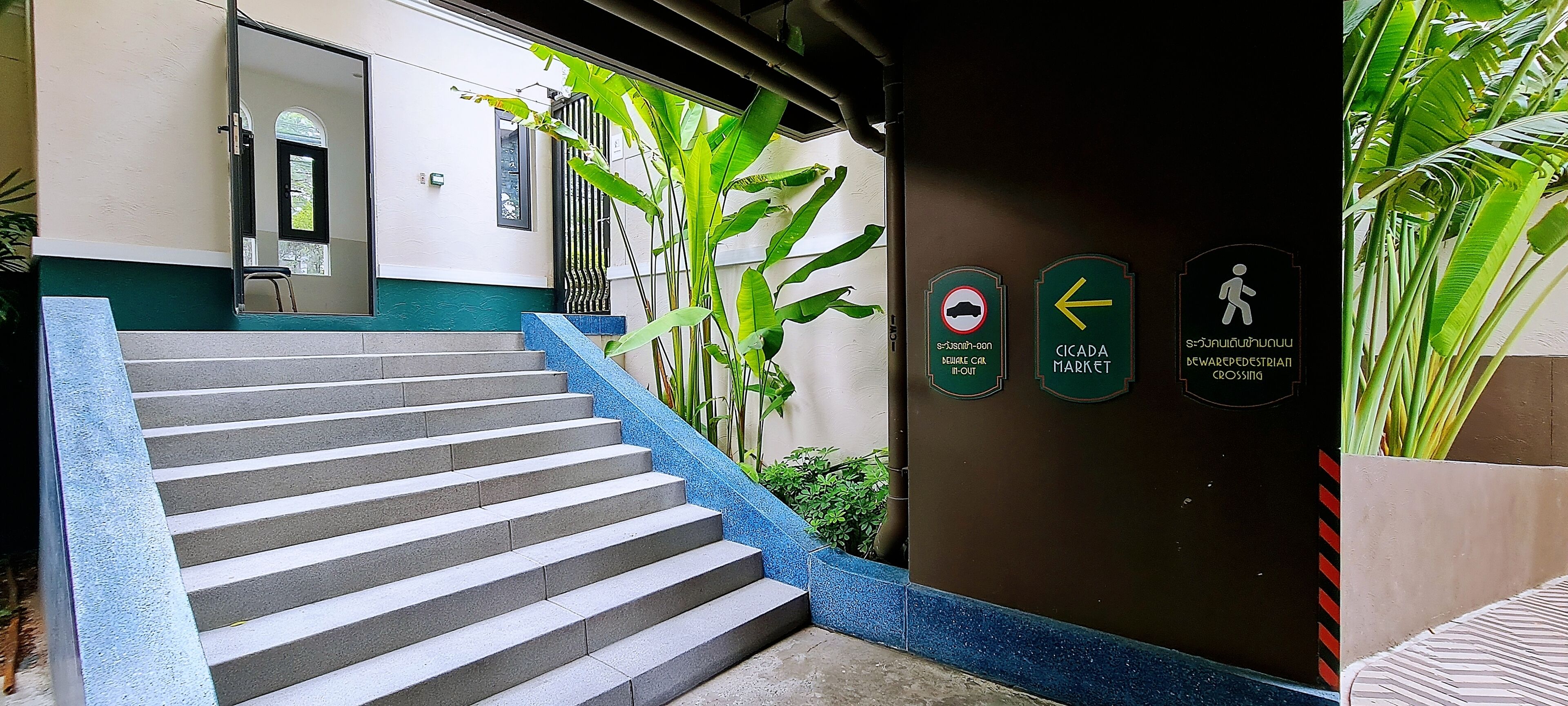 A staircase leading to a building entrance with a wall-mounted sign indicating a pedestrian crossing and a market direction.