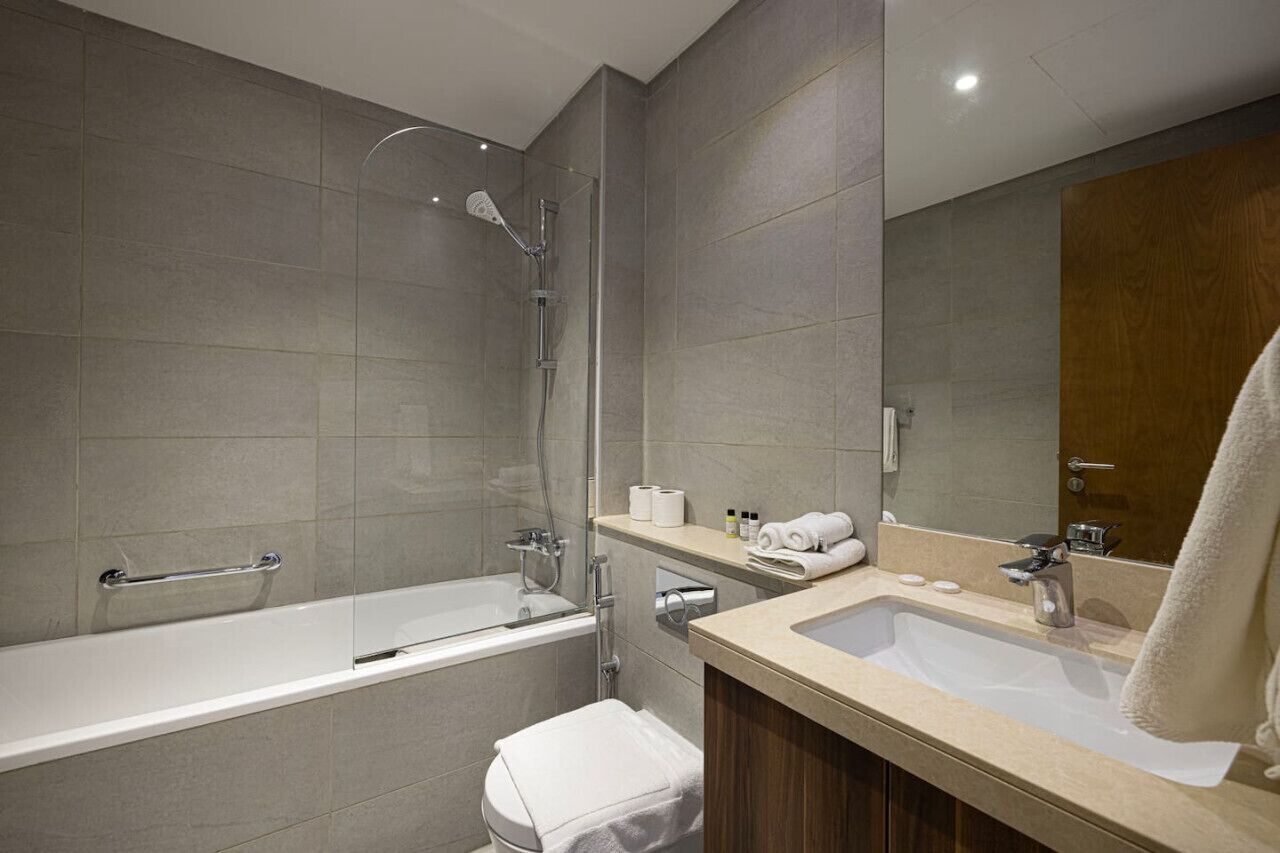 Een moderne badkamer met een bad, douche en wastafel.
