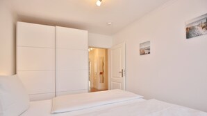 A bedroom with a bed, a wardrobe, and a door leading to another room.