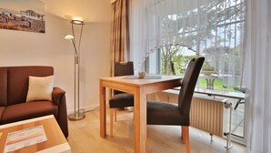 A modern hotel room with a wooden table, a brown sofa, and a large window with curtains.