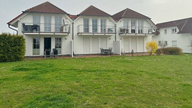 Un immeuble résidentiel de deux étages, doté d’un toit plat, de murs extérieurs blancs et de nombreux balcons.