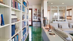 Una sala de estar moderna con piso de baldosas verdes, un sofá y una estantería llena de libros.