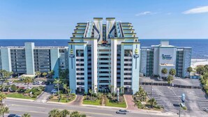 Hotel de vários andares com átrio central, estacionamento e vista para a praia.