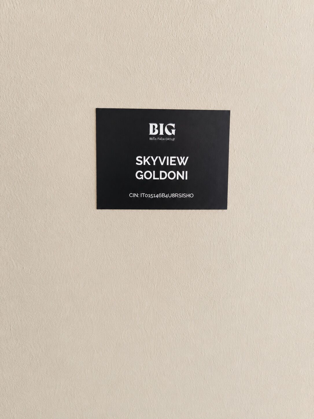 A black label with white text on a beige wall.