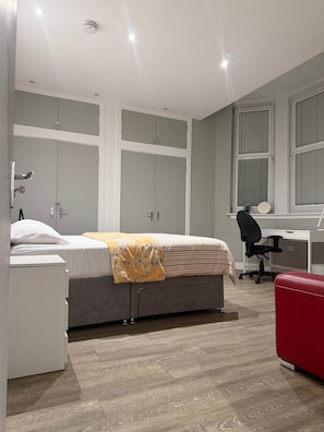 Ein modernes Schlafzimmer mit einem Bett, einem Schreibtisch und einem Sessel.