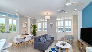 A modern living room with a grey sofa, white dining table, and a flat-screen TV. - w* | Lavishness 1BR w/ Balcony in Panama (Panamá)