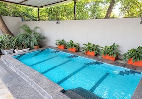 Una piscina rectangular con agua azul cristalina, rodeada por una solana de piedra.