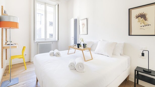 Ein Hotelzimmer mit einem großen Bett, einem Schreibtisch, einem Stuhl und einem Fenster.