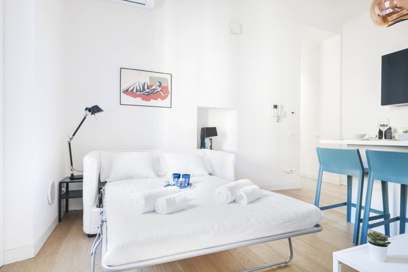 A modern hotel room with a bed, a desk, and a chair.
