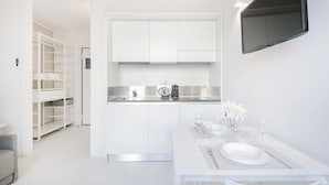A modern kitchen with white cabinetry, a built-in oven, and a flat-screen TV mounted on the wall.