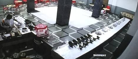 Een restaurant met een lange toonbank, meerdere tafels en een plafondventilator.