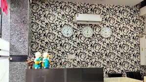 Un comptoir d’accueil avec un papier peint à motifs, un ventilateur de plafond et trois horloges.