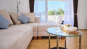 Ein modernes Wohnzimmer mit einer Couch, einem Glastisch und Blick ins Freie.