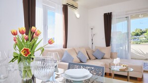 Ein helles Wohnzimmer mit einer Couch, einem Glastisch gedeckt mit Tellern und Gläsern, und einer Vase mit Tulpen.