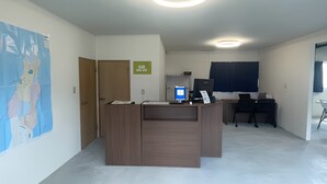Ein Empfangsschalter mit einem Computer, einer Schreibtischlampe und einem Schild an der Wand.
