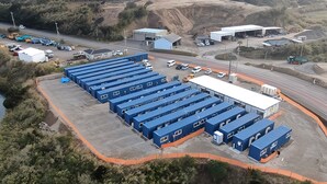 Ein großes Industriegebiet mit mehreren blauen Versandcontainern, einer Straße und einigen Gebäuden.