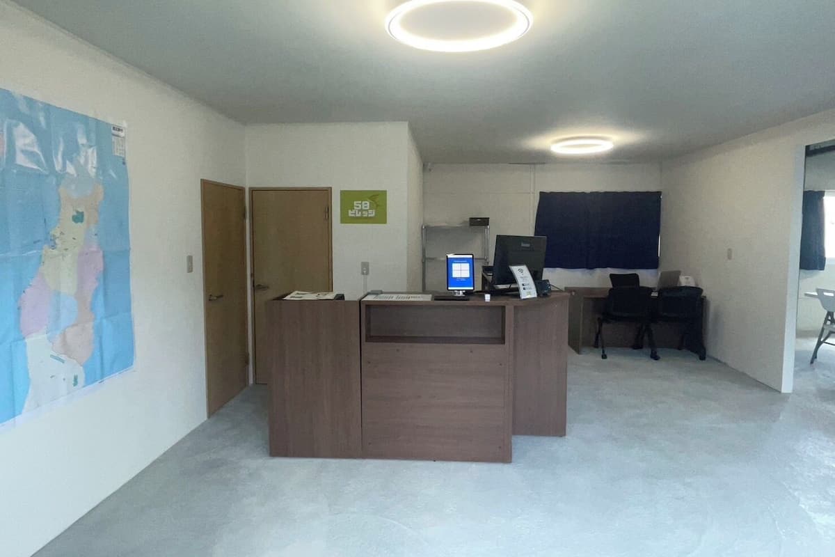 A reception desk with a computer, a chair, a door, and a poster on the wall.