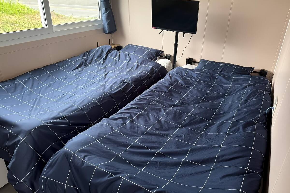 A room with two single beds, a TV, and a window with a view of the street.