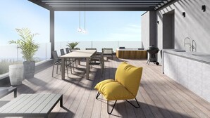 Eine moderne Terrassenanlage mit Holztisch und -stühlen, einem gelb gepolsterten Sessel, einer Bar und großen Kübelpflanzen.