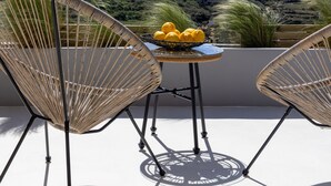 A terrace with wicker chairs and a table with lemons, overlooking a hilly landscape. - The Hydor Element Of Gaea (Tinos)