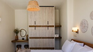 A bedroom with a bed, a wardrobe, a bedside table, a mirror, and a hanging light fixture. - The Pyr Element Of Gaea (Tinos)