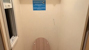 A small wooden toilet with a hinged seat, a window above it, and a sign on the wall. - Mobile Home au Ranch du Bonheur, Évasion à la Ferme (Tourtouse)