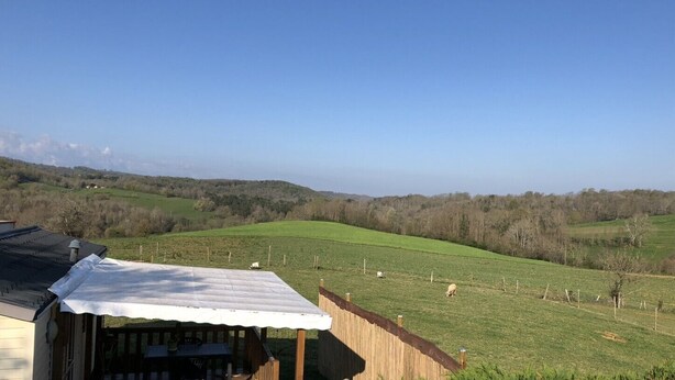 A rural landscape with a fenced pasture, a wooden structure with a white roof, and a clear blue sky. - Mobile Home au Ranch du Bonheur, Évasion à la Ferme (Tourtouse)
