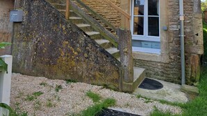Un edificio de piedra con una escalera de madera que lleva a una puerta.
