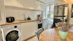 Una cocina moderna con armarios blancos, horno empotrado, lavavajillas y refrigerador de acero inoxidable.