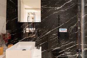 A modern bathroom with a black marble sink and a glass shower enclosure. - Kolonaki Chic Minimalist Studio-Athens (Athens)
