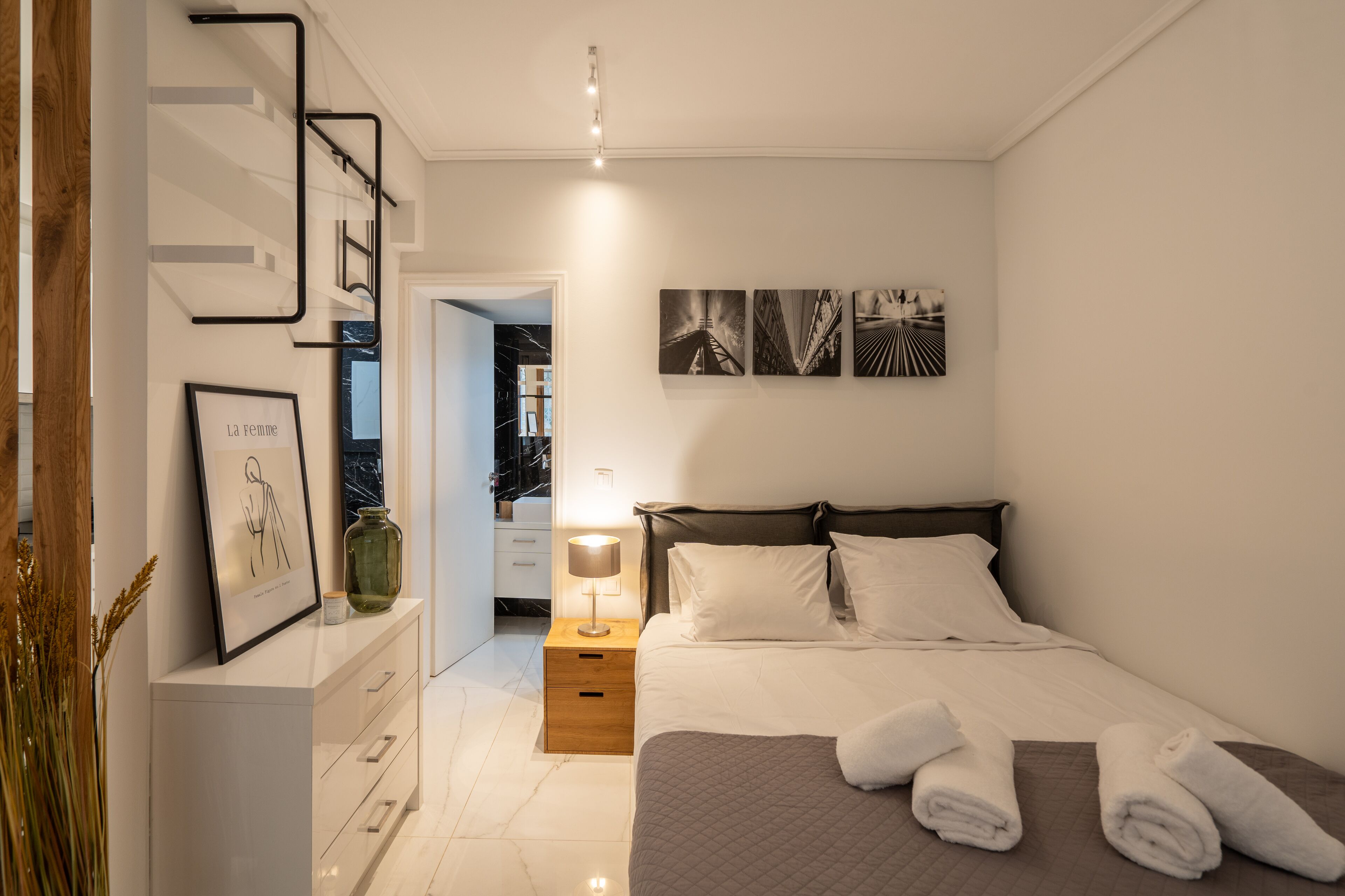 A modern bedroom with a bed, bedside table, and wall art.