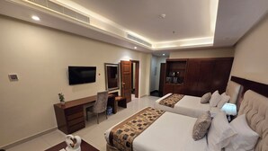 Habitación de hotel con dos camas, un escritorio, una silla, un televisor y un minibar.