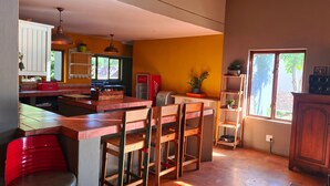 A kitchen with a central island, wooden chairs, a red refrigerator, and a window with a view of greenery. - The Captain. Country Stay Near The City. Pet Friendly! (Pretoria)