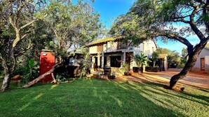 A house with a paved courtyard, surrounded by trees and greenery. - The Captain. Country Stay Near The City. Pet Friendly! (Pretoria)