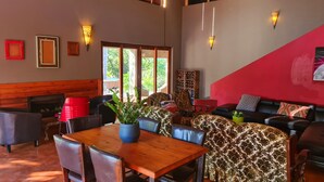 A cozy indoor seating area with a wooden table, chairs, a sofa, and a fireplace. - The Captain. Country Stay Near The City. Pet Friendly! (Pretoria)
