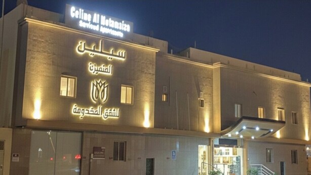 A hotel with a sign in Arabic and English, a covered entrance, and a visible staircase leading to the lobby. - Celine Al Motamayza Apartments (Jeddah)