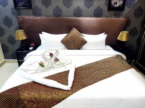 Ein Hotelzimmer mit Bett, Kissen, Nachttisch, Lampe und einer Wand mit einem gemusterten Design.