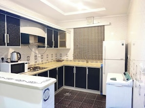 Eine kompakte Küche mit Mikrowelle, Wasserkocher und Kühlschrank.
