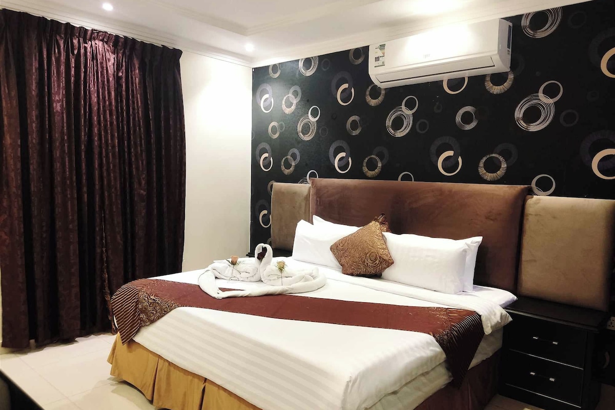 Ein Hotelzimmer mit Bett, Nachttisch, Klimaanlage und Vorhang.