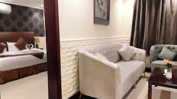 A hotel room with a bed, a sofa, a coffee table, and a painting on the wall.