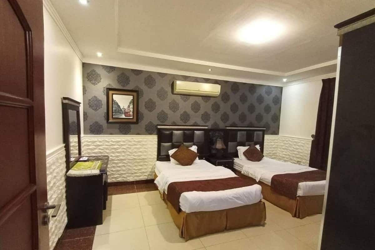 Habitación de hotel con dos camas, una mesita de noche, un espejo y un equipo de aire acondicionado en la pared.