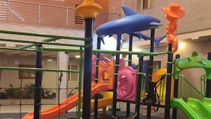 A playground with various play structures including slides and climbing areas, surrounded by a safety net. - Celine Al Motamayza Apartments (Jeddah)
