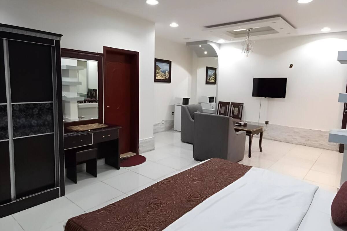 Una habitación de hotel moderna con una cama grande, un escritorio, una silla, un televisor y un armario.