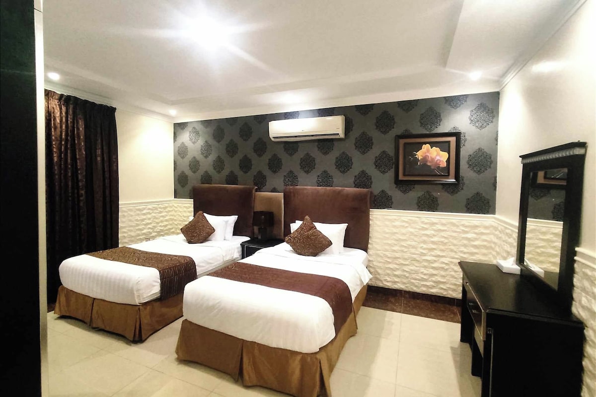 Ein Hotelzimmer mit zwei Betten, einem Flachbildfernseher und einer Klimaanlage an der Wand.