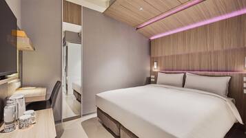 A modern hotel room with a large bed, a desk with a chair, a television, and a mirror.
