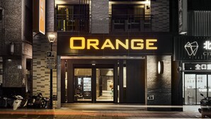 Een gebouw met een opvallend 'ORANGE' bord, een parkeersignaal en een etalage met glazen ingang.