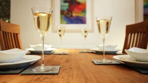 A dining table with three glasses of white wine, plates, and cutlery. - Spacious dog friendly apartment by the beach, private garden and sea views. (Padstow)