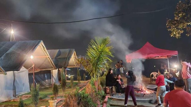 A campsite with tents, a fire pit, and people gathered around. - Nama Stay Home (Pokhara)